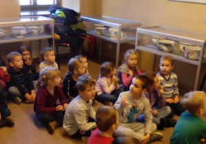 Dzieci siedzące w sali z wystawą nocników.